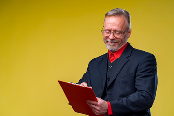 Middle aged businessman holding file folder. Horizontal format isolated on yellow background.