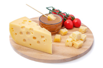 piece of cheese, saucer with honey and tomato on a wooden board, triangular cheese piece, isolated white background