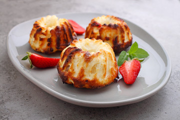 Cottage cheese casserole in a plate decorated with mint and strawberry on a concrete background.