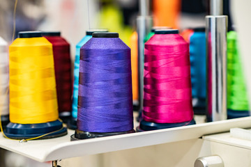 Coils with colored threads. Silk threads on bobbins. Light industry. Clothing manufacture. Sewing...