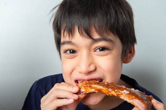 Little boy eating rib pork grill with happy face