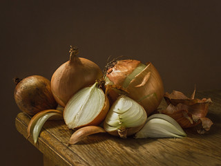 Juicy yellow onions, on a wooden table, with a dark background, soft light. Imitation of a Dutch kitchen still life. Mono food. - 351824925