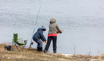 Obraz na płótnie Canvas Mom and son are fishing in the lake for fishing rod.