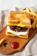 Homemade Grilled Cheese Burger with French Fries on a rustic wooden board, low angle view.