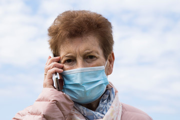 senior woman using mobile phone with  medical mask. Safety measures during the coronavirus outbreak