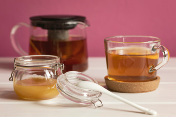 Honey in glass pot and cup of black tea with lemon. Healthy eating concept.