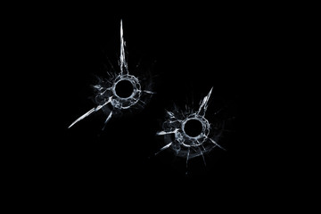 two bullet hole in glass close up on black background