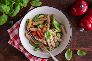whole grain penne pasta with grilled vegetables ( zucchini, peas, bell pepper ant tomato) and cheese on bowl