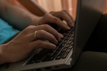 A man is typing on a laptop keyboard, photographed from the side.