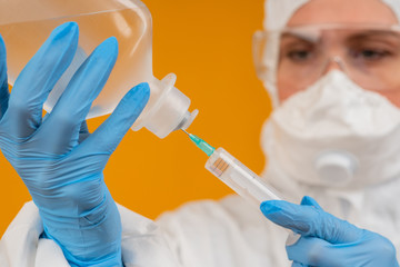 Face of a girl in a protective suit, a syringe and a container o