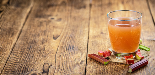 Rhubarb Juice on rustic background (close up; selective focus)