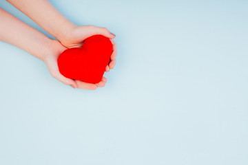 Children's hands hold a red heart. Child Health Care Concept