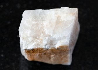 closeup of sample of natural mineral from geological collection - raw Calcite rock on black granite background