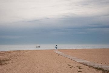 Fototapeta premium Man looks at the sea with a boat.