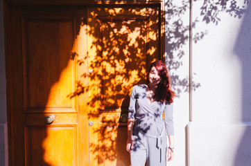 Redhead young adult smiling in front of a wood door