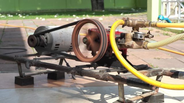Rusty and old water pump motor working, Rotating pulley and belt on air pump machine