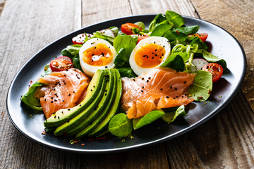 Salmon salad - smoked salmon boiled egg and vegetables on wooden background
