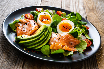 Salmon salad - smoked salmon boiled egg and vegetables on wooden background
