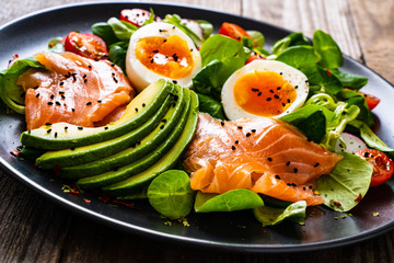 Salmon salad - smoked salmon boiled egg and vegetables on wooden background
