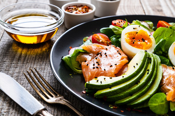 Salmon salad - smoked salmon boiled egg and vegetables on wooden background
