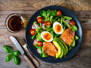 Salmon salad - smoked salmon boiled egg and vegetables on wooden background
