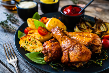 Barbecue chicken drumsticks with vegetables on wooden table
