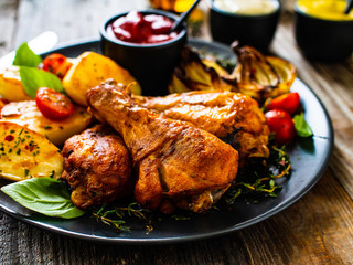 Barbecue chicken drumsticks with vegetables on wooden table
