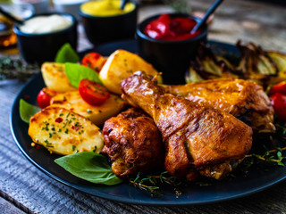 Barbecue chicken drumsticks with vegetables on wooden table
