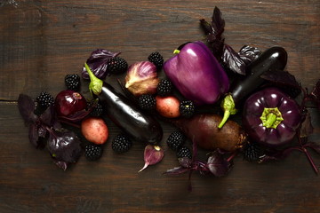 Raw organic purple vegetables on a dark background. View from above