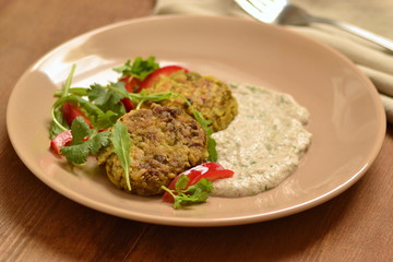 Lentil fritters with zucchini. Served with fresh vegetables and sauce.