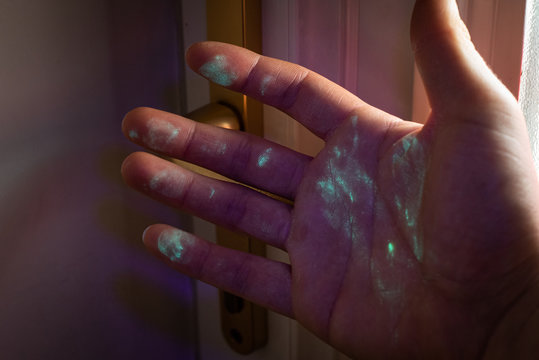 hand covered in bacteria or virus after touching door handle. Visualisation under UV light.
