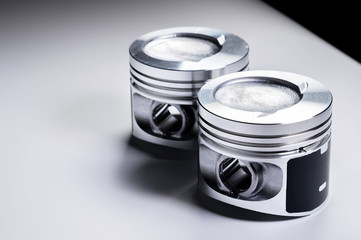 Close-up of two new internal combustion engine piston on a gray gradient background. The concept of new spare parts of the internal combustion engine