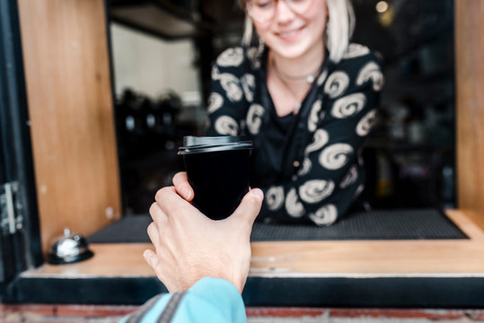 A Customer's Hand Is Picking Up A Take Away Coffee In A Small Cafe