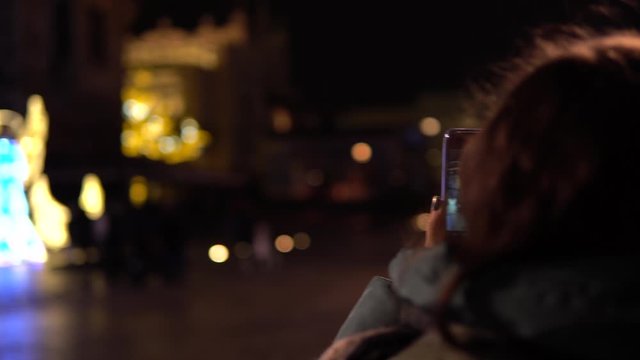 In the evening a girl makes a photo of Krakow's sightseeing  with her smartphone.