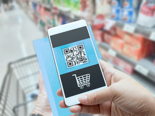 Online order grocery shopping on touch screen concept. Woman hand holding smart phone and scanning QR code for ordering ingredients food which delivery service at home for cooking.