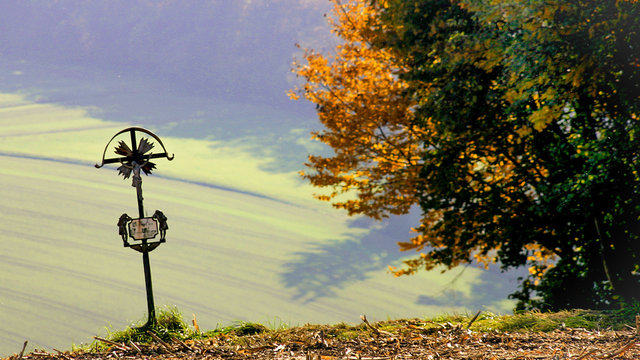 Wegkreuz wacht &uuml;ber ein sanftes Tal im herbstlichen Sonnenlicht