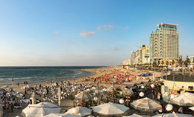 Central crowded beach of Tel Aviv on sunny day. Seascape and skyscrapers, Israel.