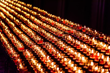Obraz premium Yellow and red candles in the church in the darkness