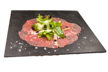 Gourmet Carpaccio with arugula, on a black stone plate, isolated on white background