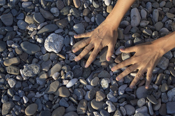 Woman hands touching stones on the beach