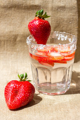 A refreshing drink of strawberries in a glass and berries on a background of a napkin made of...