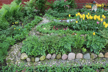 Flower garden with pebble paths, flowerbeds and garden figurine