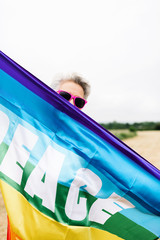 modern granny with pink sunglasses holding gay pride flag. vertical stock image. LGBT rights concept and old age.