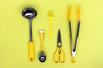 kitchen ladle accessories, scissors, tongs, brush, yellow ice cream spoon on a yellow background