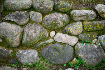 Old stone wall of stones with moss and grass