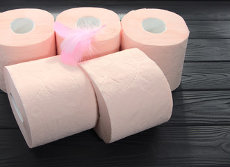 Pink toilet paper is on the table. Paper rolls for personal hygiene on a black background.