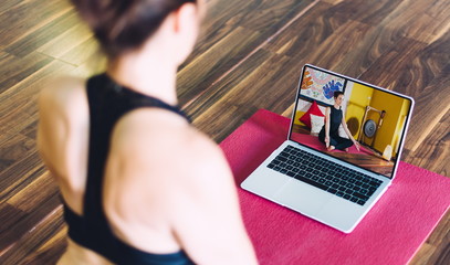 Young woman following yoga classes at a distance on a laptop. concept of yoga classes on the internet