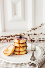 Breakfast in the morning. Cottage cheese pancakes with jam  on white plate. Russian, Ukrainian cuisine. Spring flowers