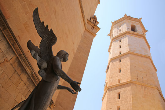 Statue of an angel against the background of  el fadri historic bell tower in the city of Castell&oacute;n, Valencia, Spain.