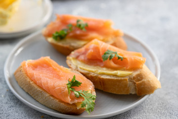 Bruschetta with smoked salmon and butter on concrete background. Delicious snack or appetizer.Close up